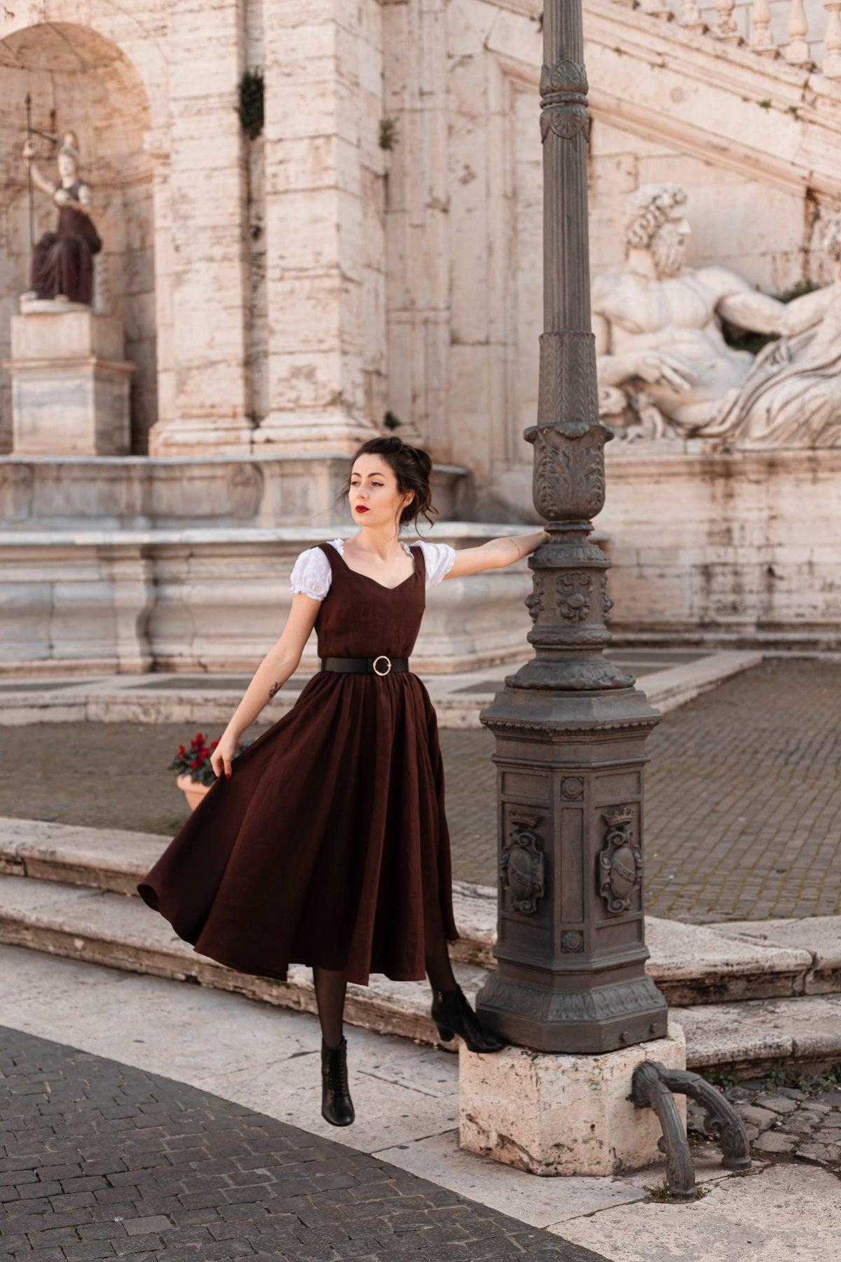 Andalusia dark brown linen dress with a full circle skirt and black belt, posing by an old lamppost in Rome