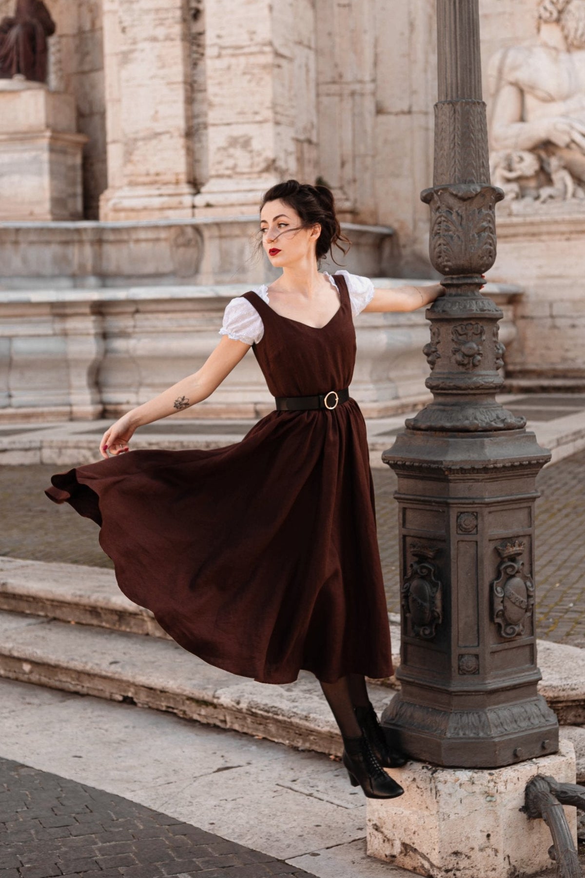 Andalusia dark brown linen dress twirling to show the full circle skirt, worn over a white blouse in Rome