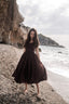Andalusia dark brown linen dress with a full circle skirt photographed on a rocky seaside