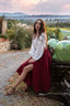 Seated view of the Ellie burgundy linen midi skirt showing the front slit and flowing shape