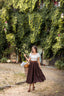 Full-length view of the Ellie dark brown linen midi skirt photographed in a rustic stone courtyard