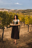 Full-length front view of the Estella moss green linen corset styled among sunlit grapevines