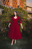 Full-length front view of the Siena burgundy linen midi dress photographed in a romantic garden