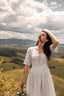 Three-quarter view of the Under the Tuscan Sky ivory wedding dress against the Tuscan hills
